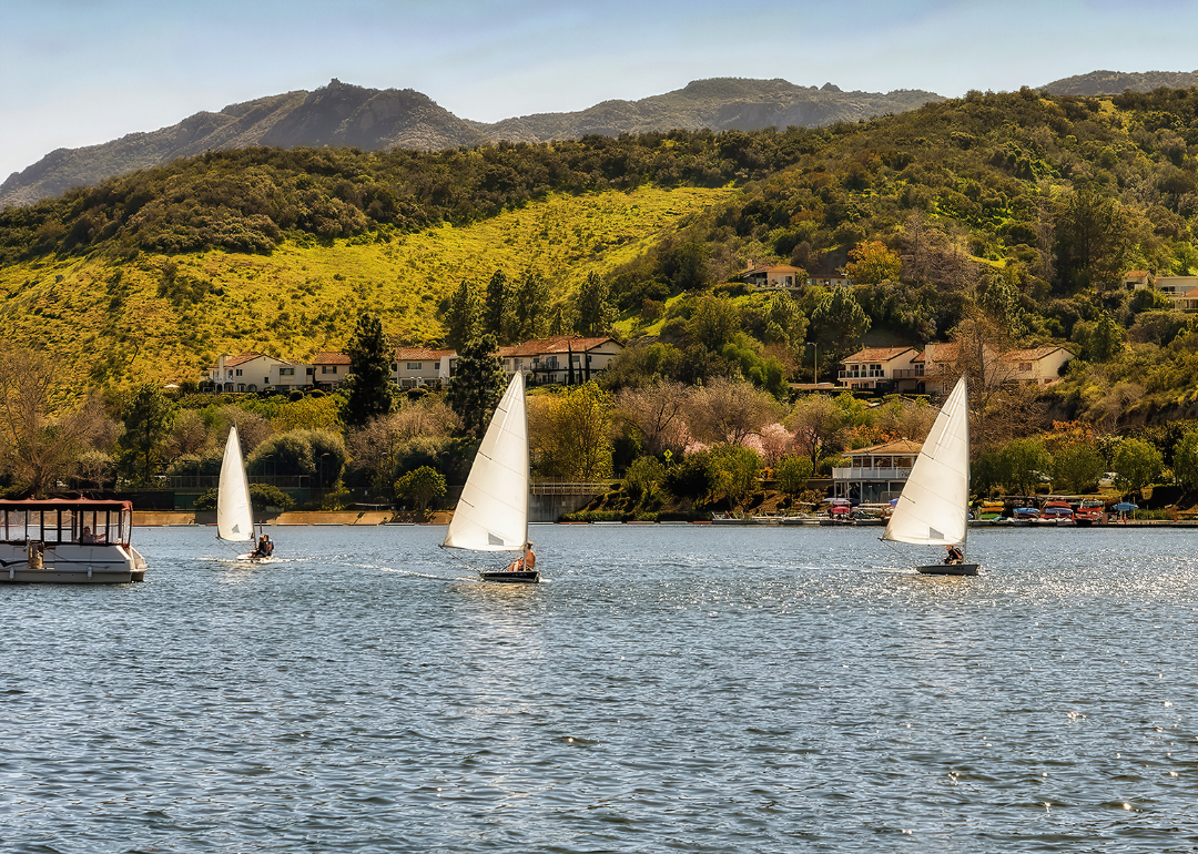 People on small sailboats on the water in the hills.