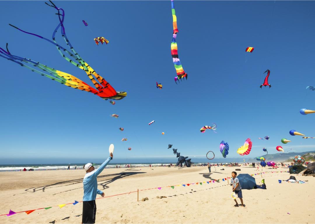 People flying colorful kytes on the beach.
