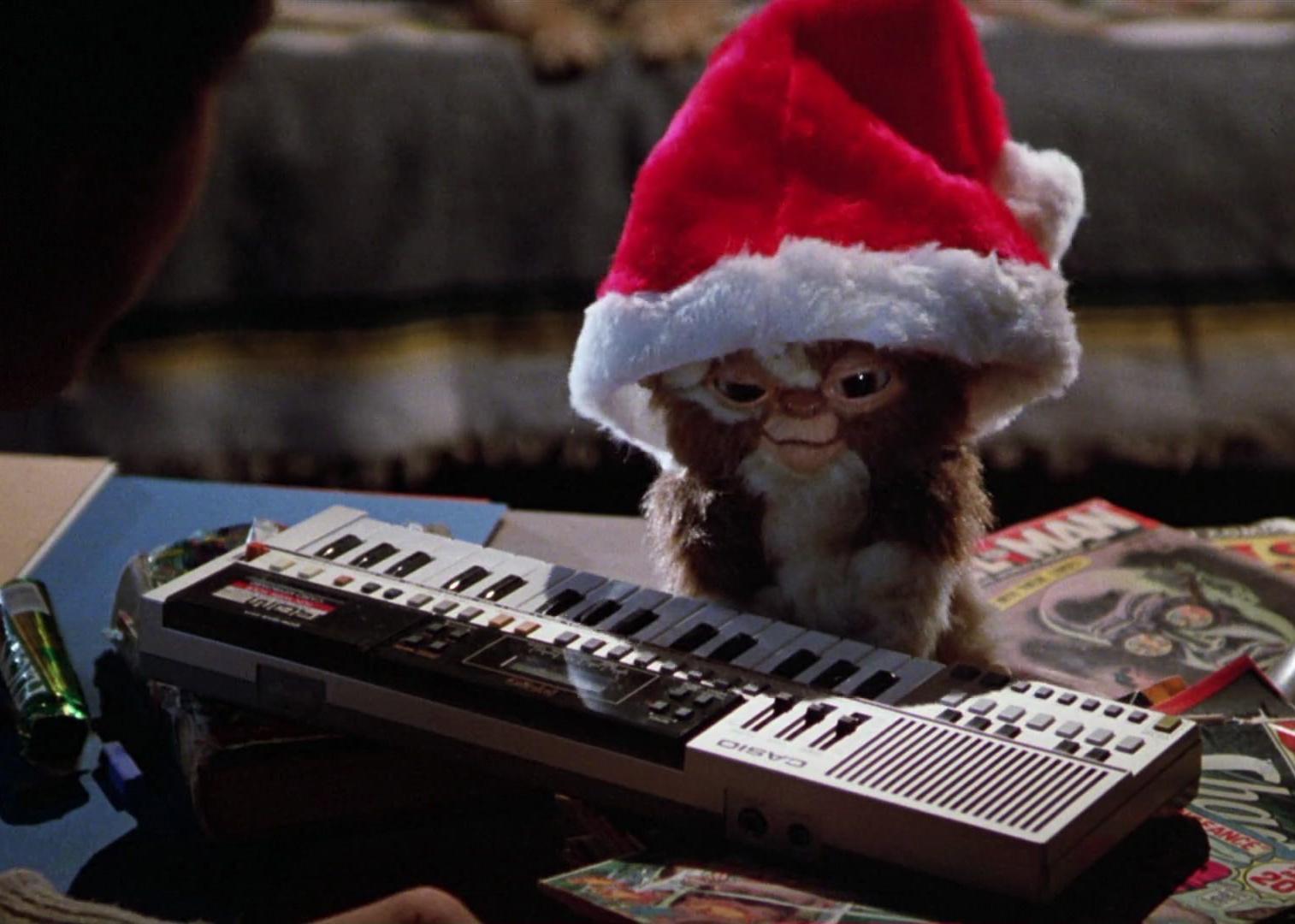 A small creature in a santa hat playing a keyboard.