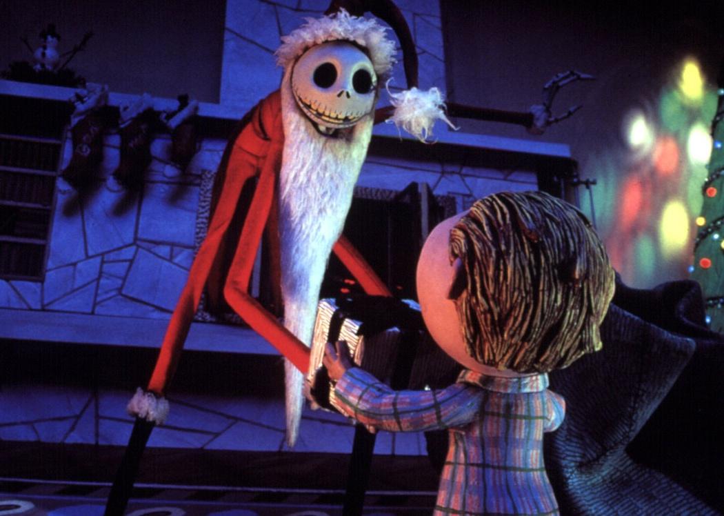 An animation of a little boy and a skeleton in a santa suit by a Christmas tree.