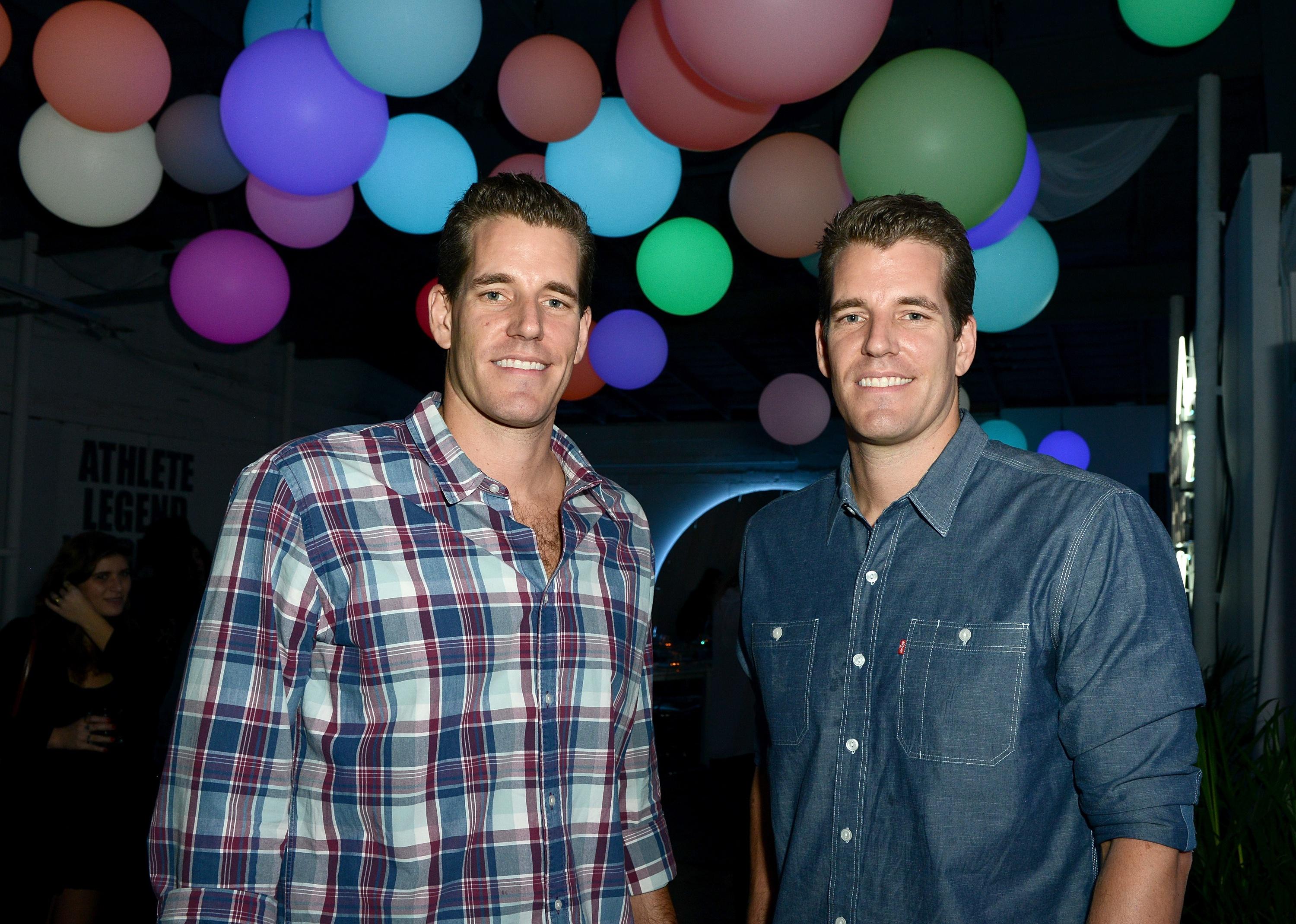Tyler and Cameron Winklevoss in front of colorful balloons.