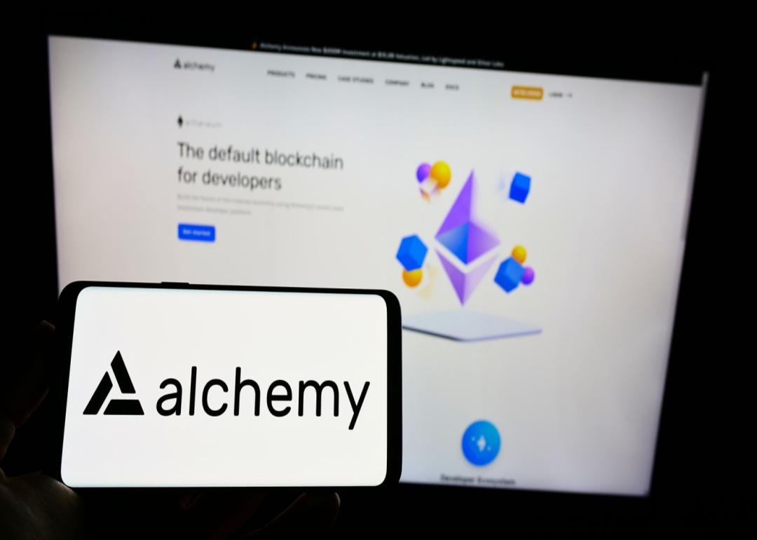 A phone showing the Alchemy app in front of a computer screen.