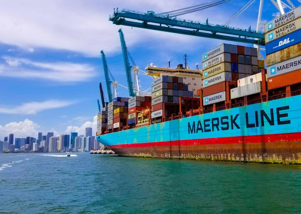 A Maersk shipping vessel loaded with containers and Miami in the background.