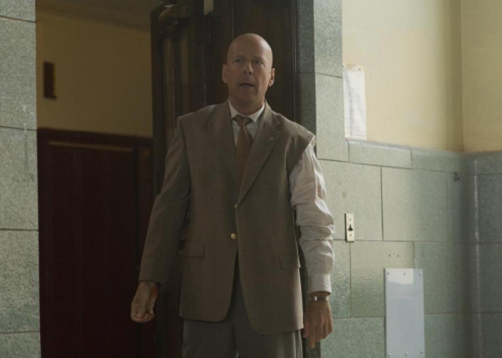 A man stands in a hallway in a suit with one of the arms torn off.