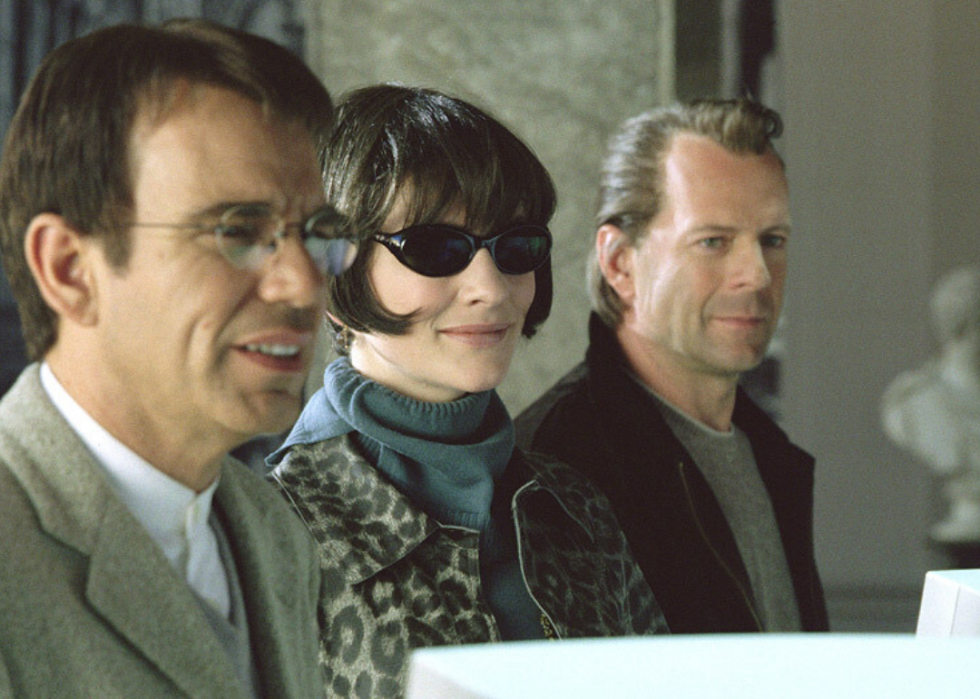 A woman and two men stand in disguises at a counter.