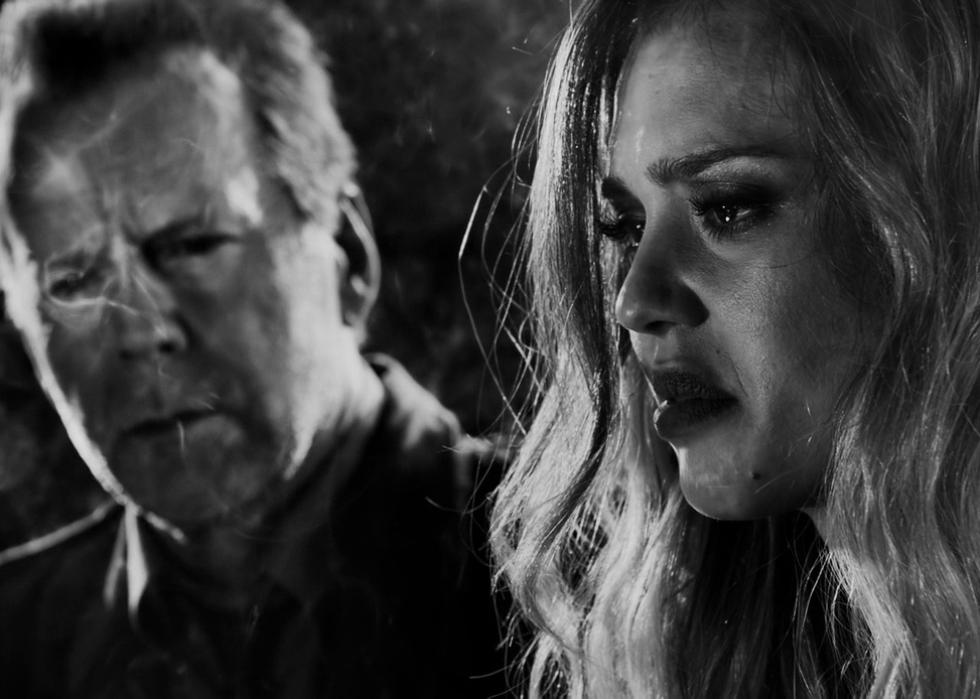 Black and white of Jessica Alba crying in the foreground and a blurry Bruce Willis in the background.
