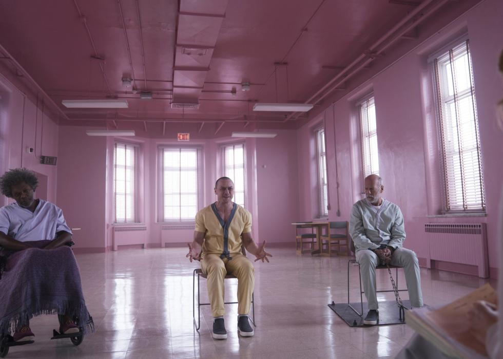 Three men sit in a pink room at a mental hospital during a therapy session.