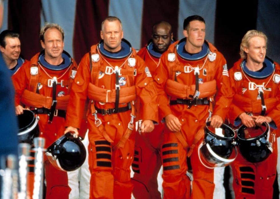 A row of astronauts in orange suits walk together with helmets in hand.Bruce Willis in "Armageddon