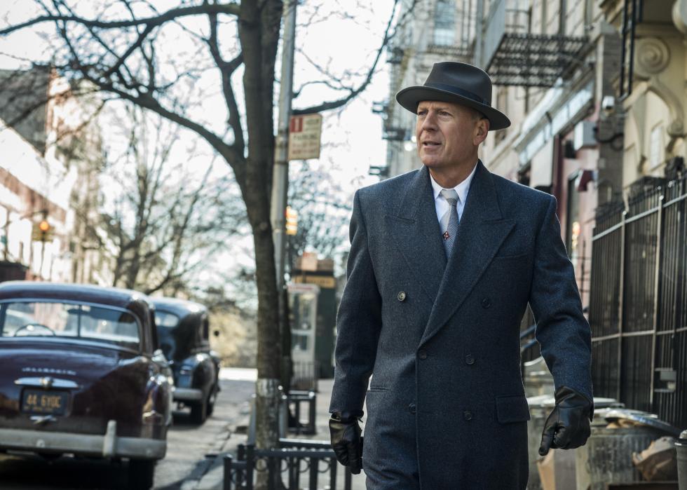 Bruce Willis walks down a street in 1950s New York.