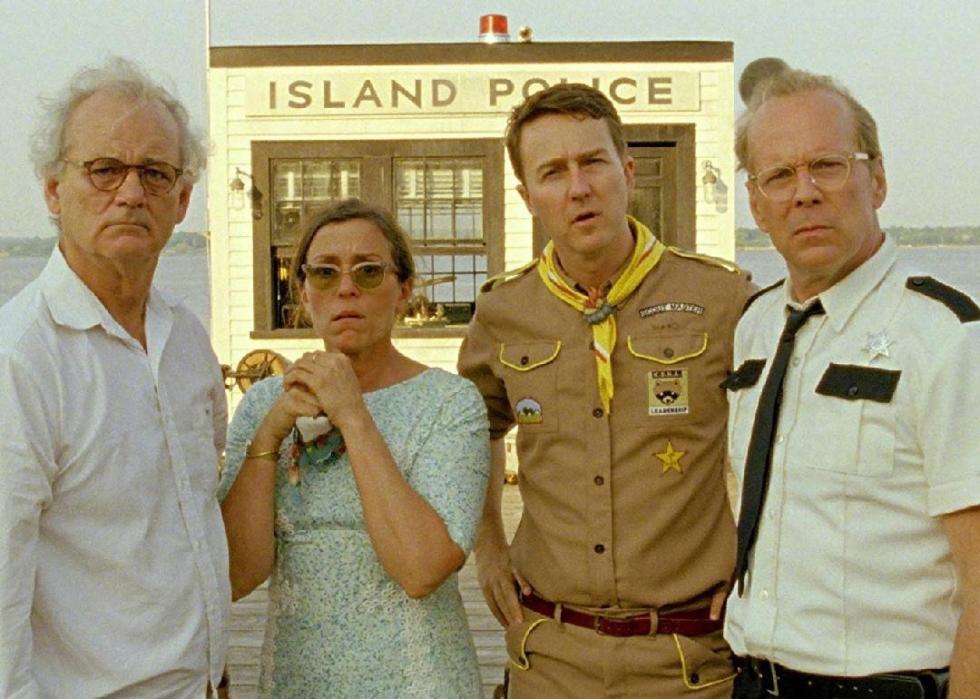 A couple, a boyscout leader and a poilice officer stand on a dock looking in shock.