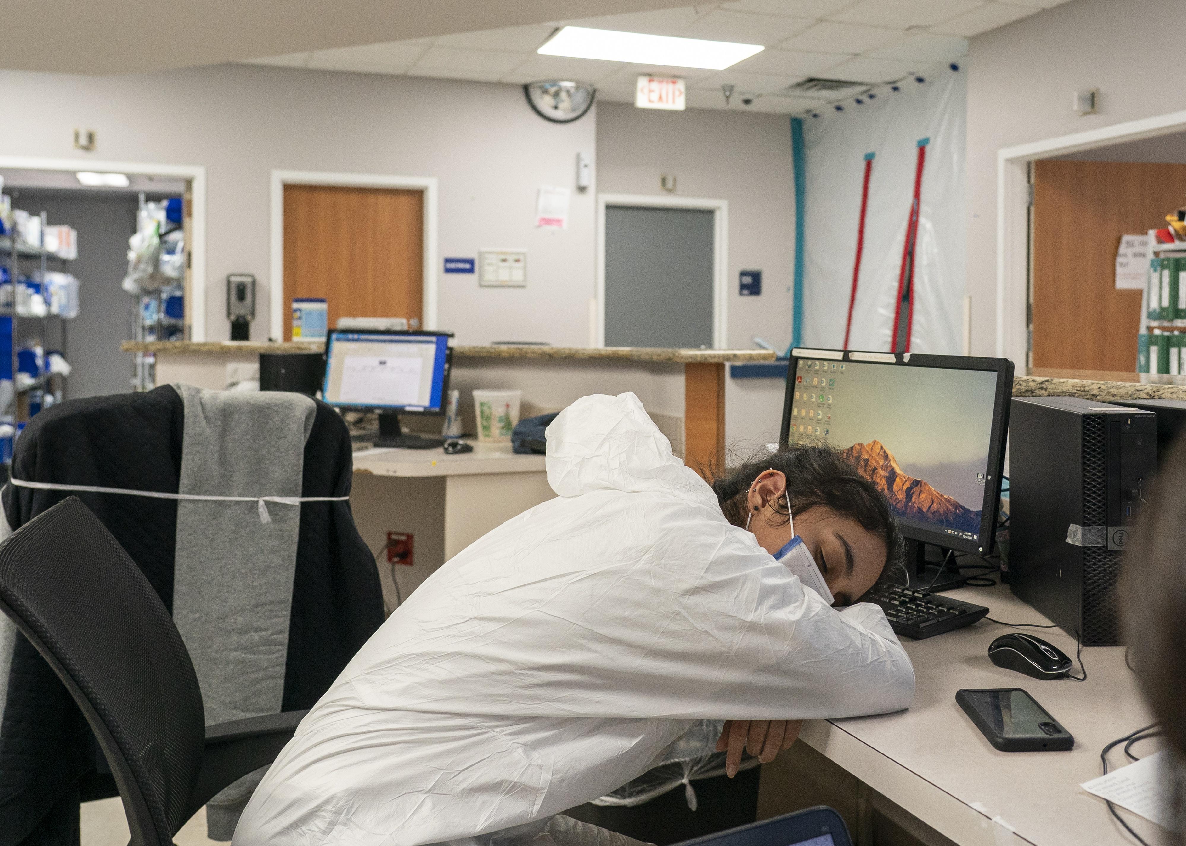 A nurse asleep on a desk with no other people in the room.
