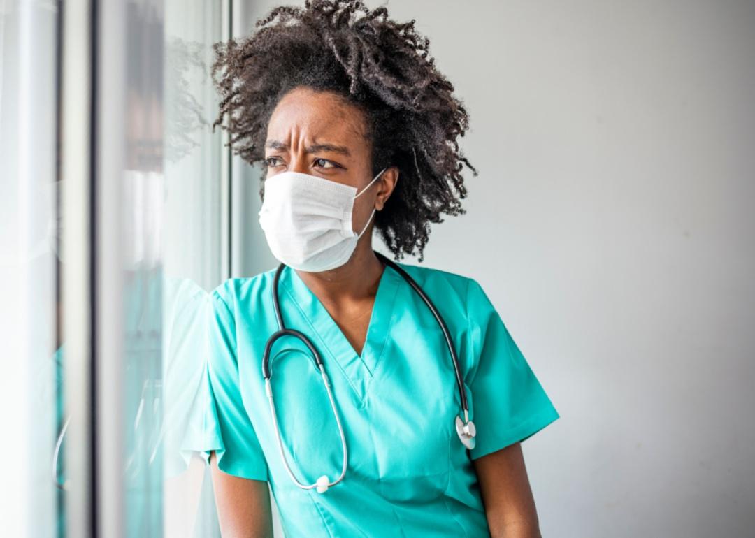 An upset nurse looking out a window.