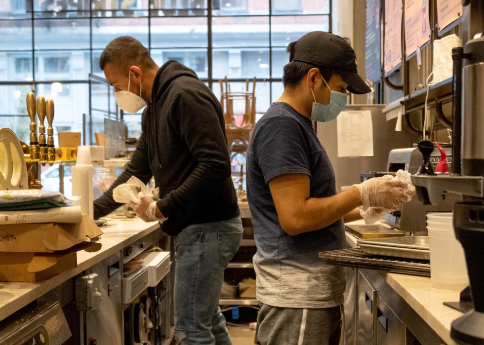 Two employees wearing masks clean inside a restaurant.
