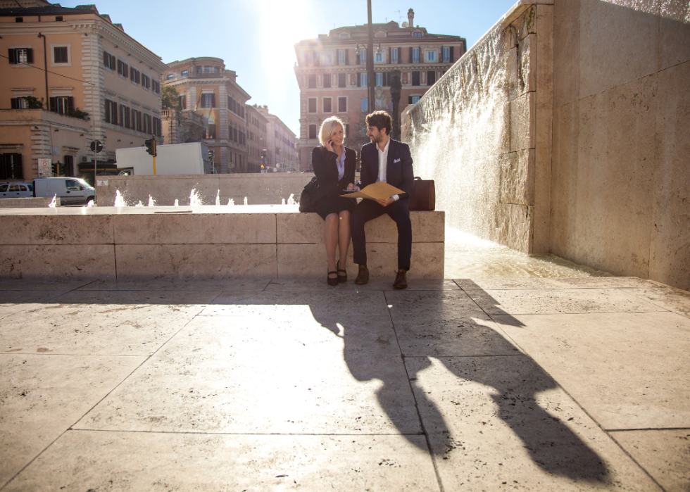 Two business people sitting by a fountain in Rome.