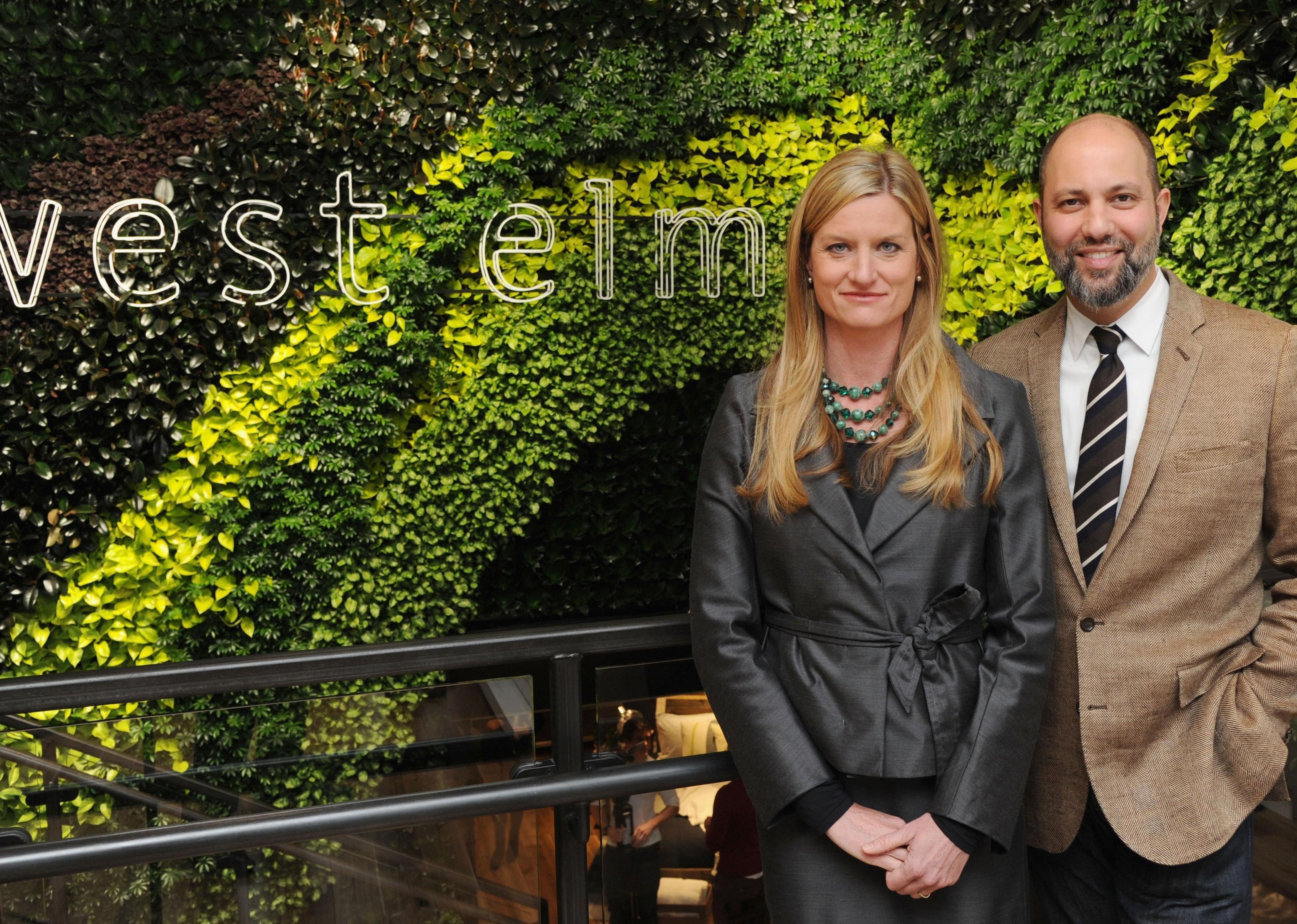 Laura Alber and Jim Brett in front of a West Elm sign in greenery.