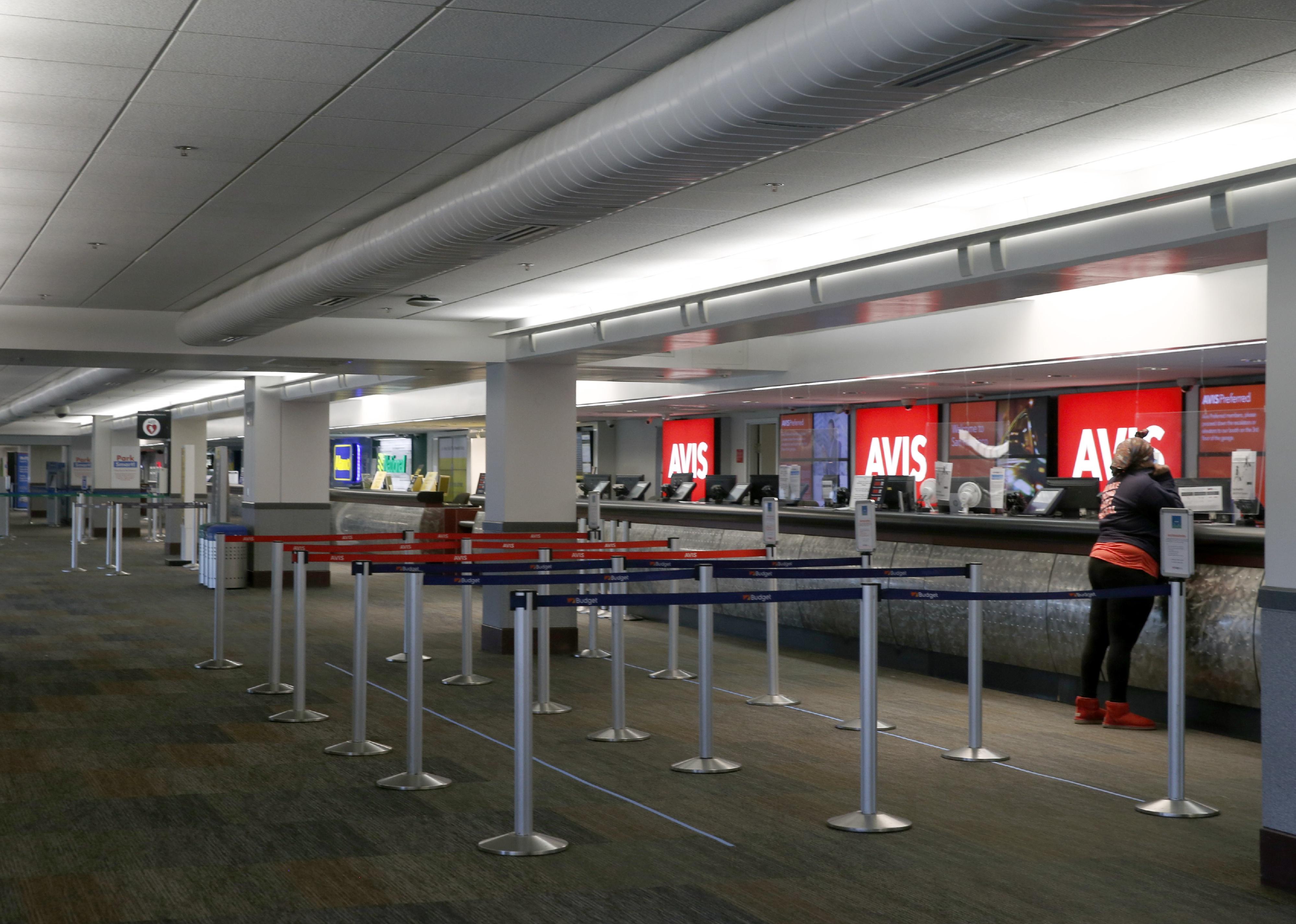 A person stands at a rental car counter.