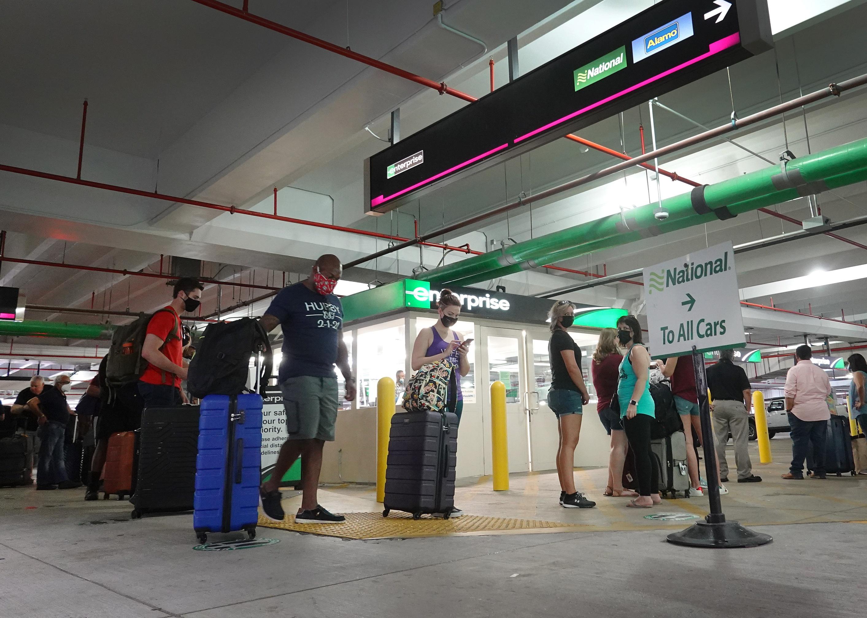 People stand in line in a rental car parking garage.