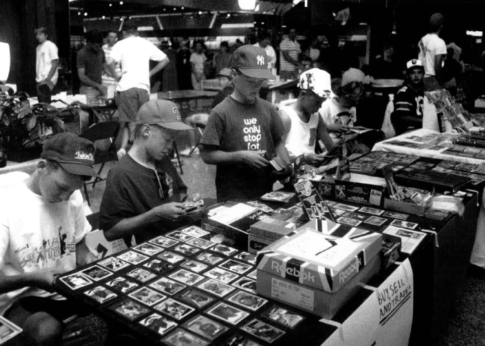 Kids at their tables loaded with many cards to trade and sell at a baseball card show.