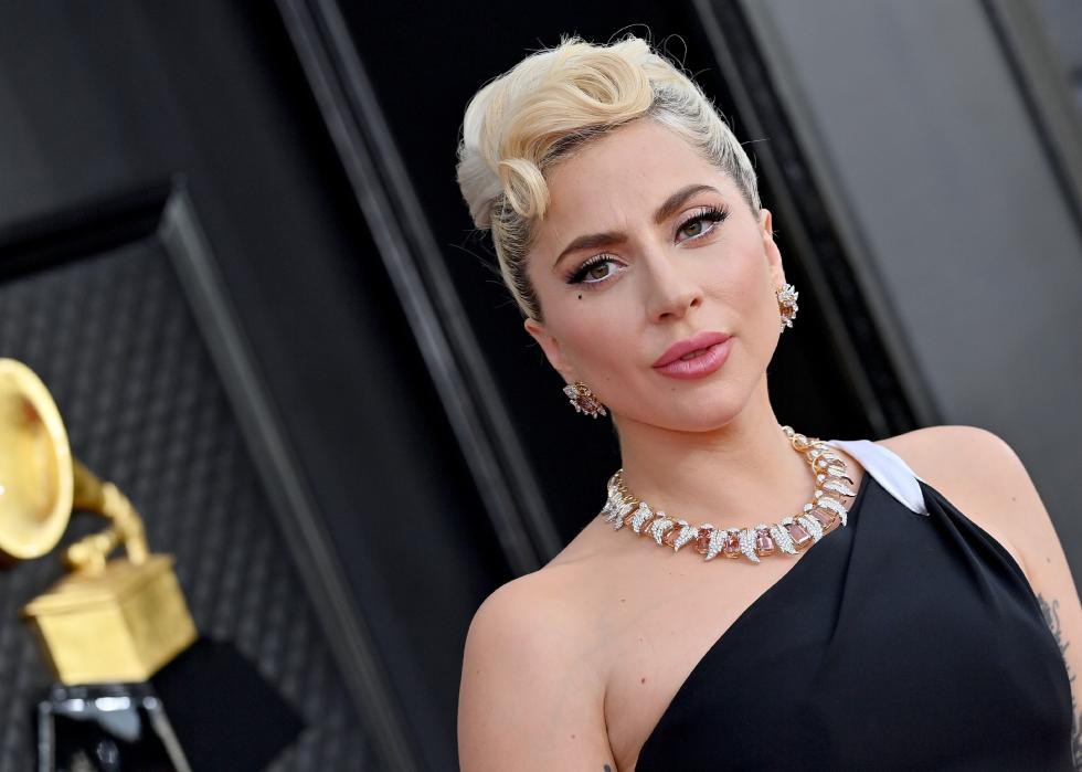 Lady Gaga in a one-shoulder black-and-white gown wearing gold jewelry and an updo.