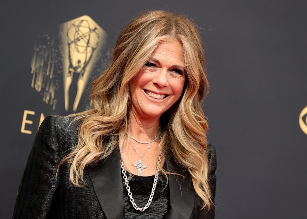 Rita Wilson smiles in front of a black background.