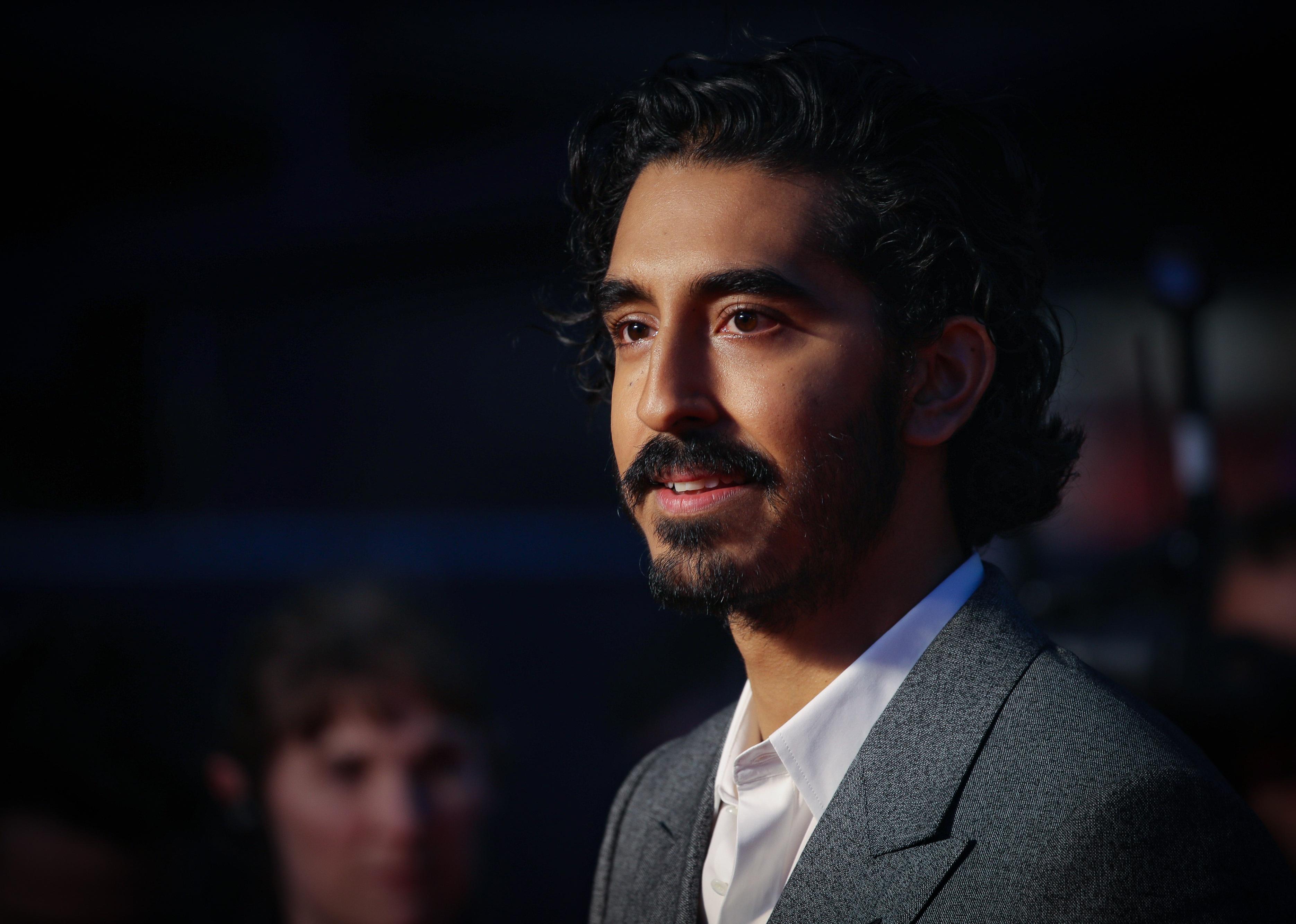 Dev Patel in a gray suit jacket.