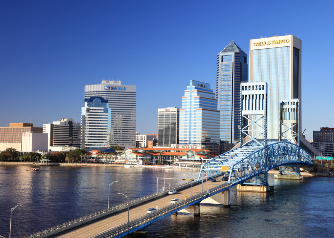 A blue bridge going over water into downtown Jacksonville.