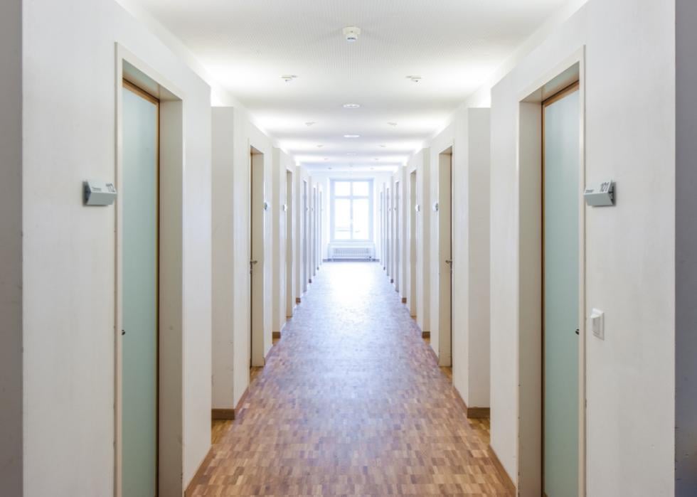 Empty hallway of light green dorm room doors.