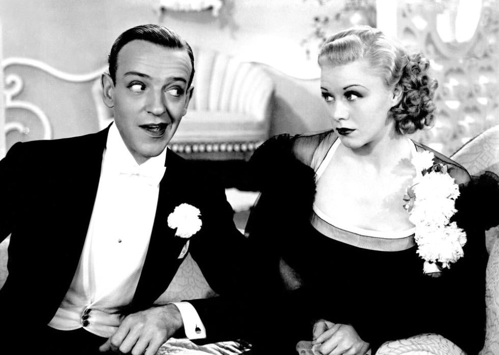 Fred Astaire and Ginger Rogers look at each other sideways while both are dressed to the nines.