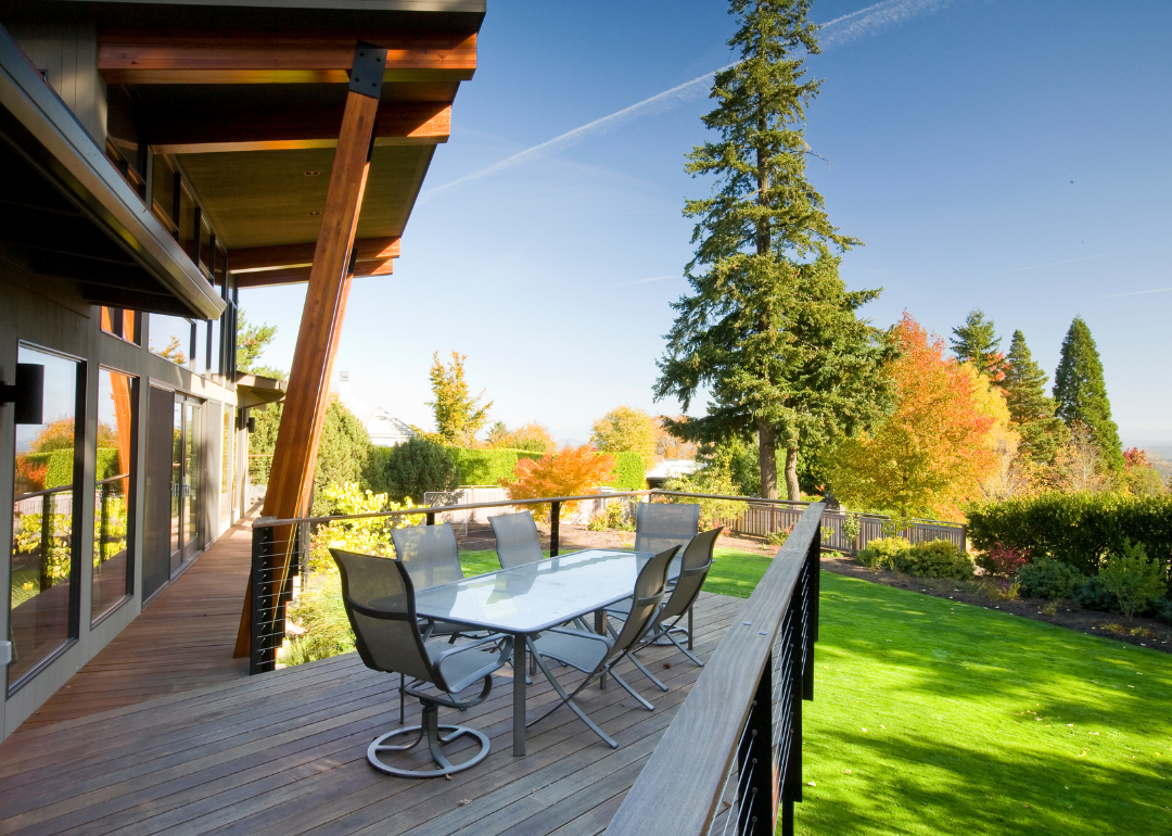The back deck of a modern home overlooking Fall trees on a hill.