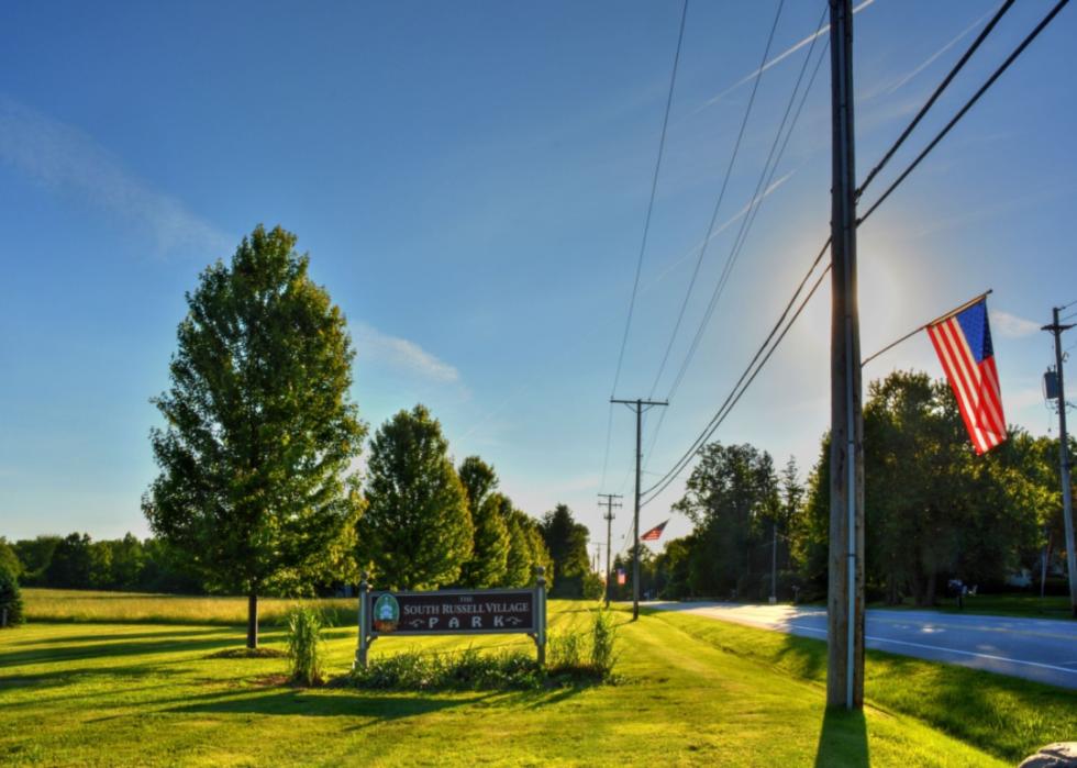 A sign entering South Russell with American flags lining the road.