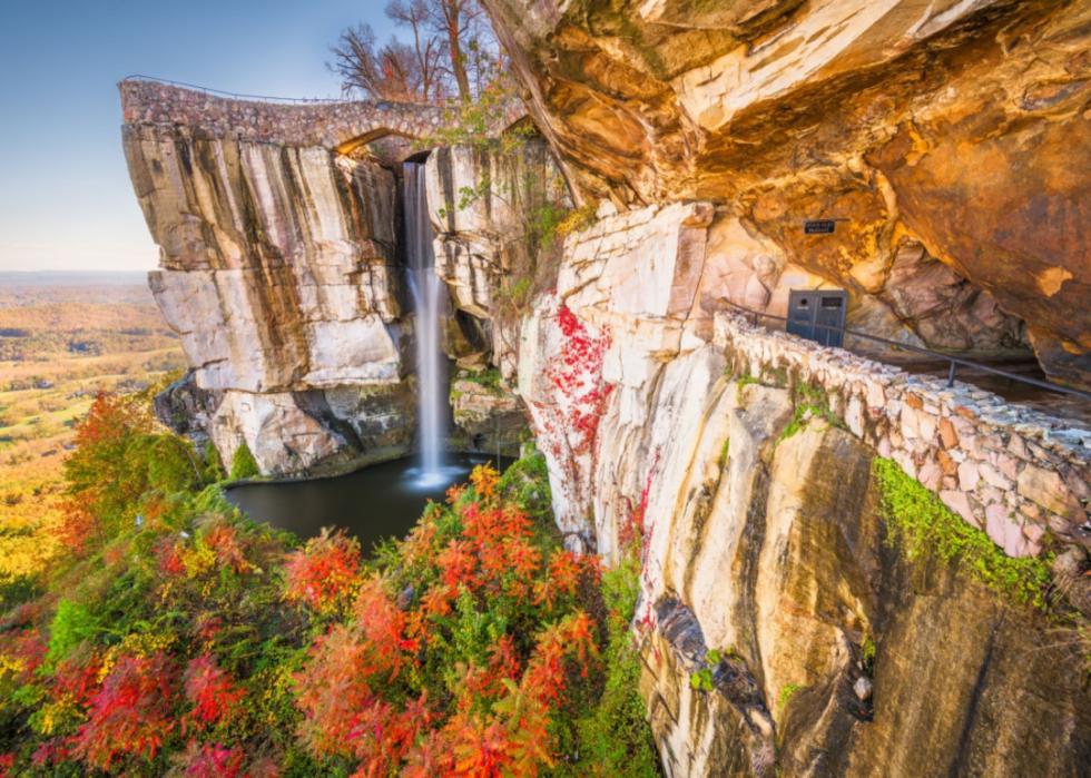 A waterfall coming off of a tall mountain cliff, surrounded by Fall trees.