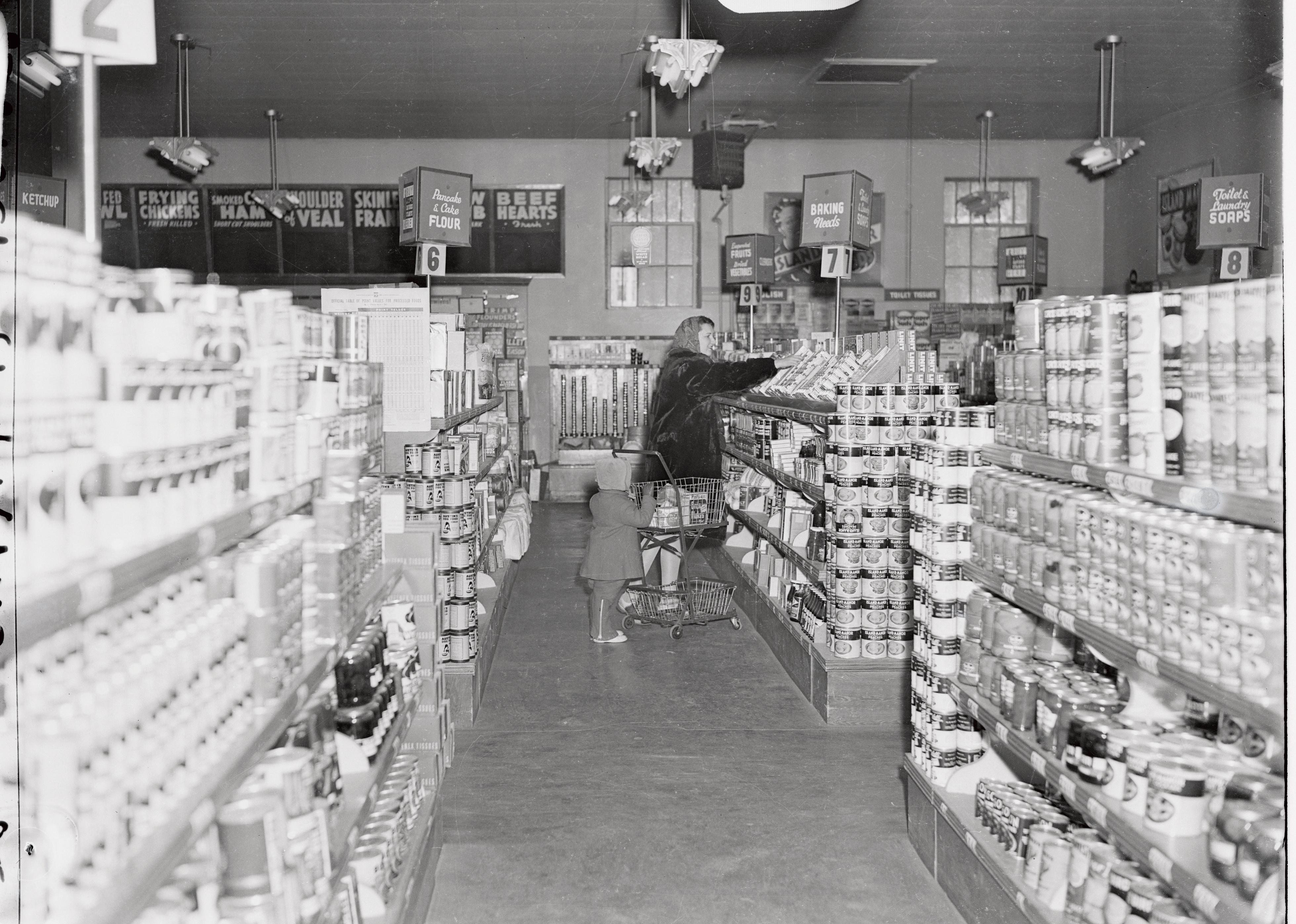A woman and child shopping in a grocery store circa 1940's.