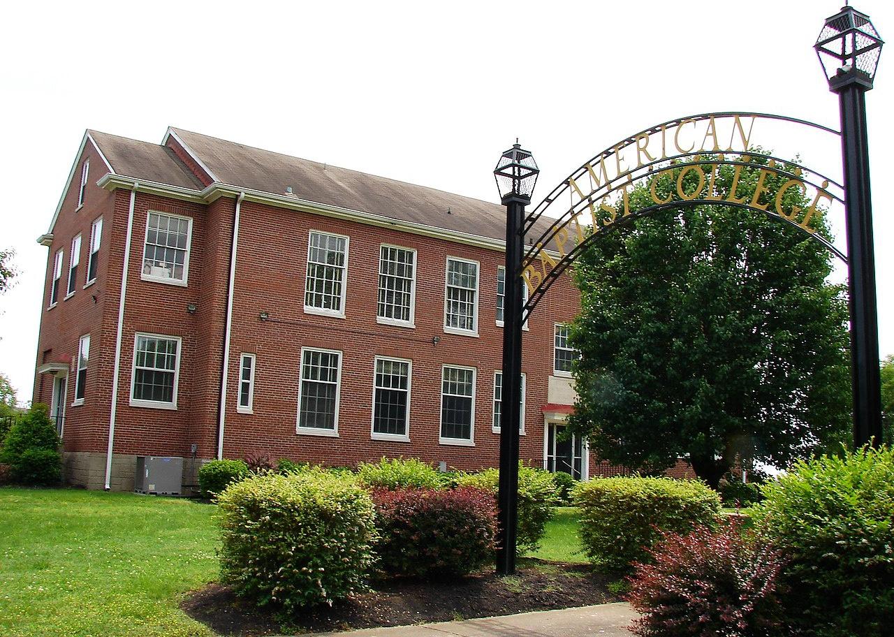 A red brick building with an iron arch sign in front.
