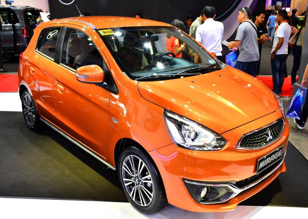 An orange Mitsubishi Mirage in a showroom.