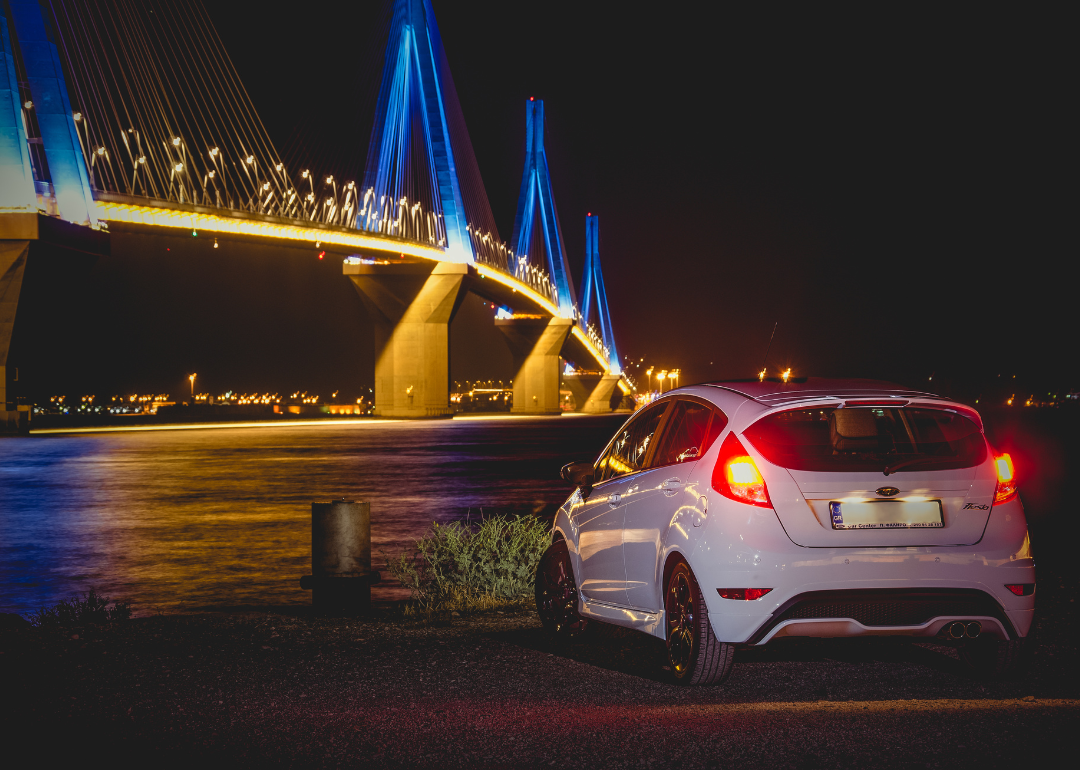 A white Ford Fiesta parked next to a bridge with blue lights.