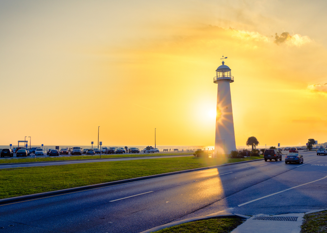 A road passing a lighthouse at sunset in Biloxi.