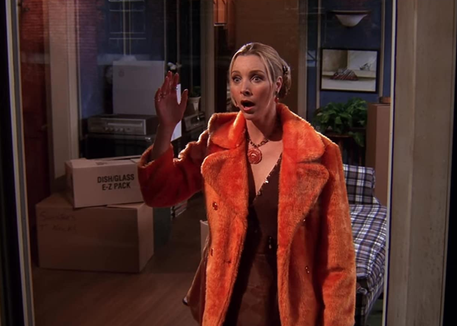 Lisa Kudrow in an orange furry coat looking surprised.