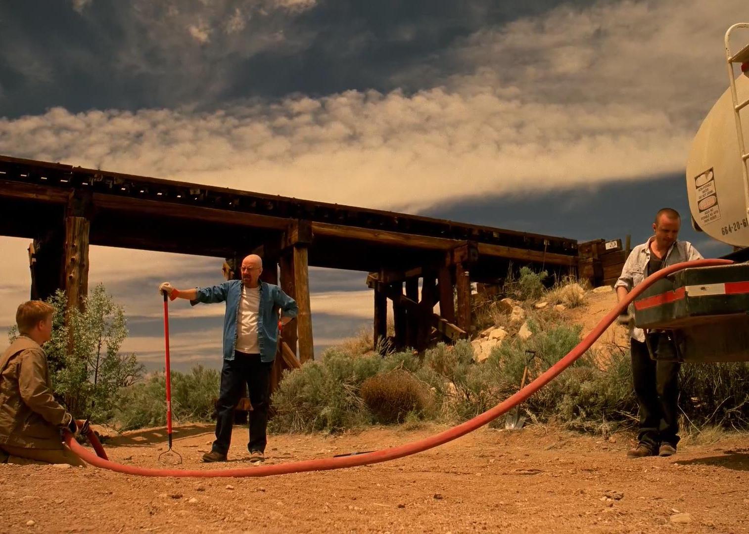 Bryan Cranston, Aaron Paul, and Jesse Plemons pump something from a truck in the desert.