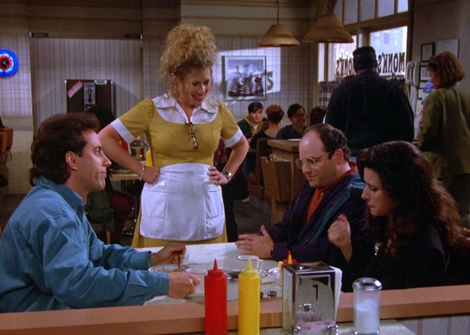 Jerry Seinfeld, Julia Louis-Dreyfus and Jason Alexander talking to a waitress in a diner.