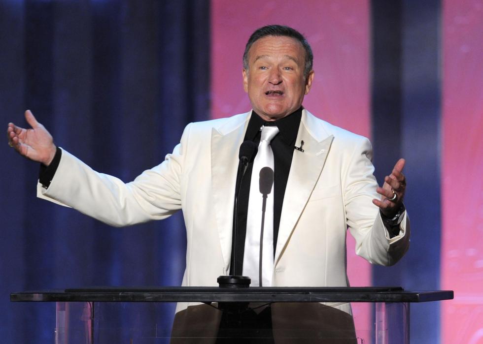 Robin Williams speaking into a mic behind a podium.