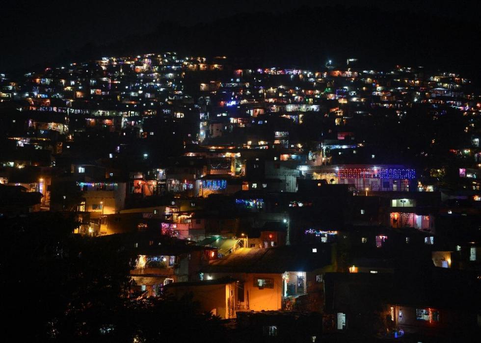 A view of a city at night from up high, with lights glowing from many houses and buildings. 