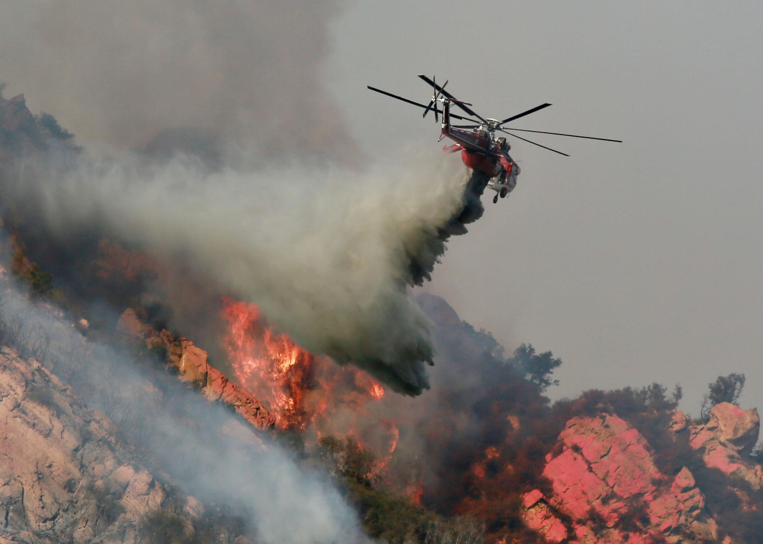  A helicopter drops flame retardant on a wildfire in Malibu, California.