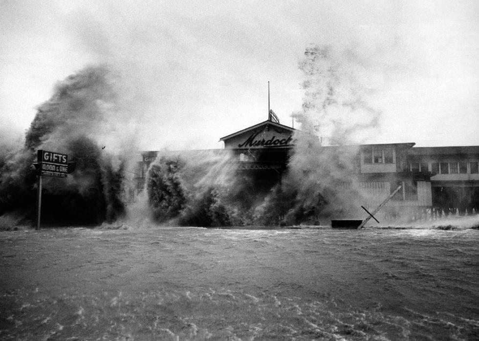 Waves crash against a building, with plumes of sea water reaching above the two-storey building.