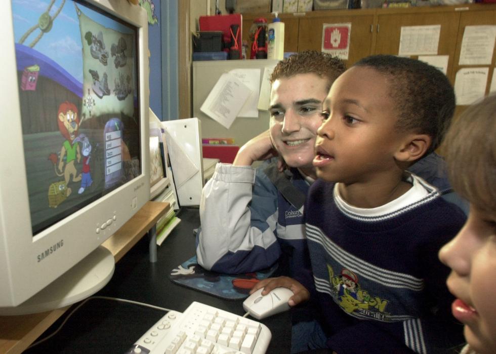Student plays with Reader Rabbit as teacher looks on