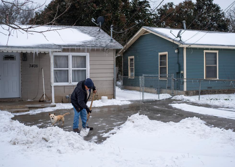 A Texas resident clears snow from his driveway alongside his dog.