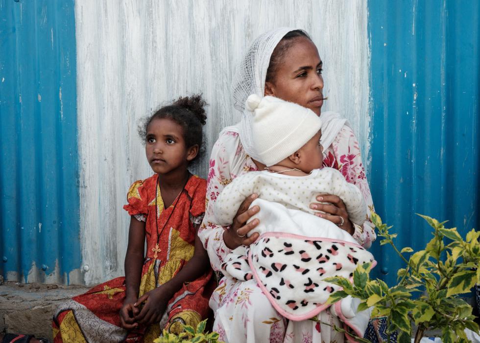 An displaced mother sits next to and carries a child in Ethiopia