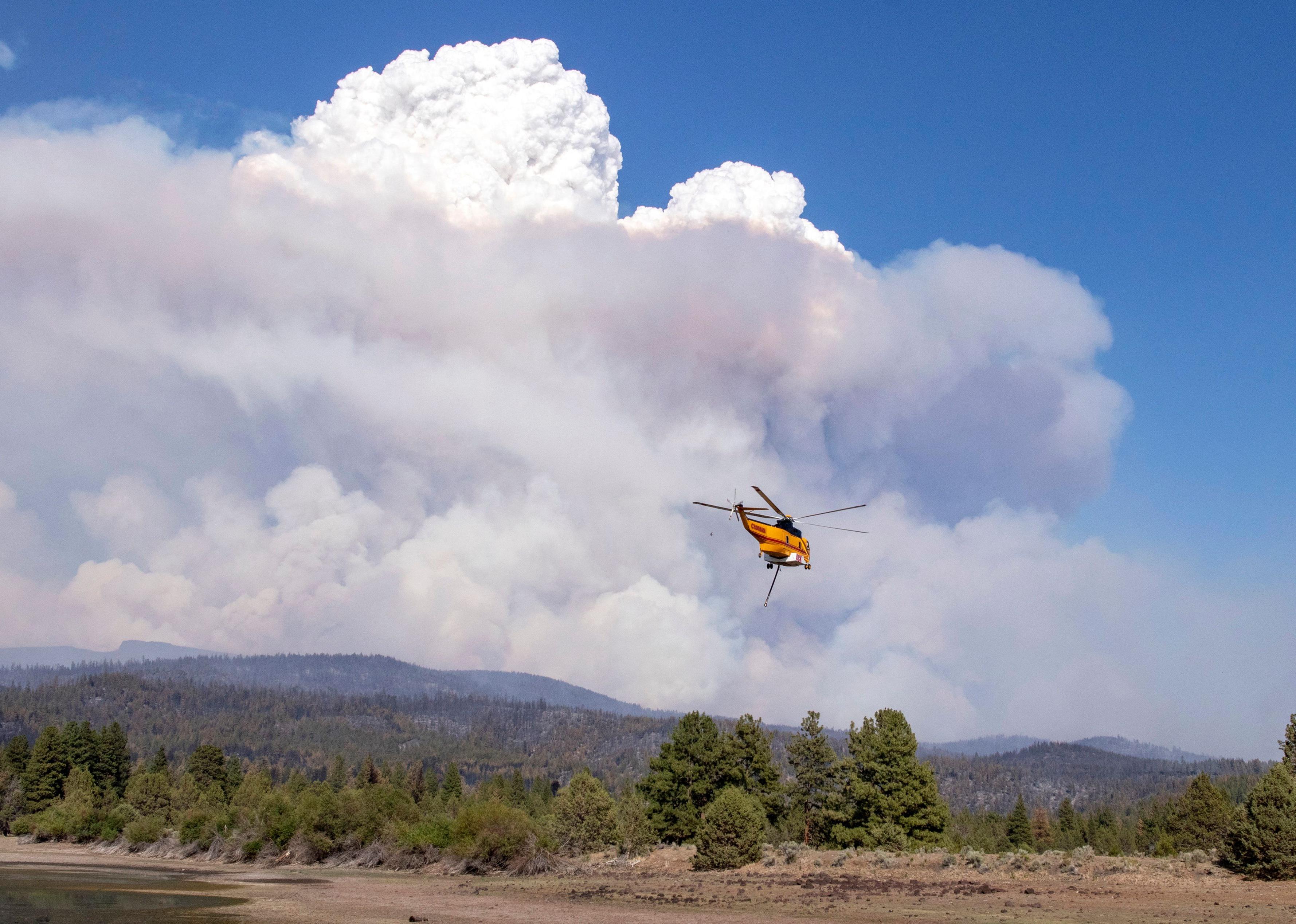 A helicopter flies with a load of water for a fire.
