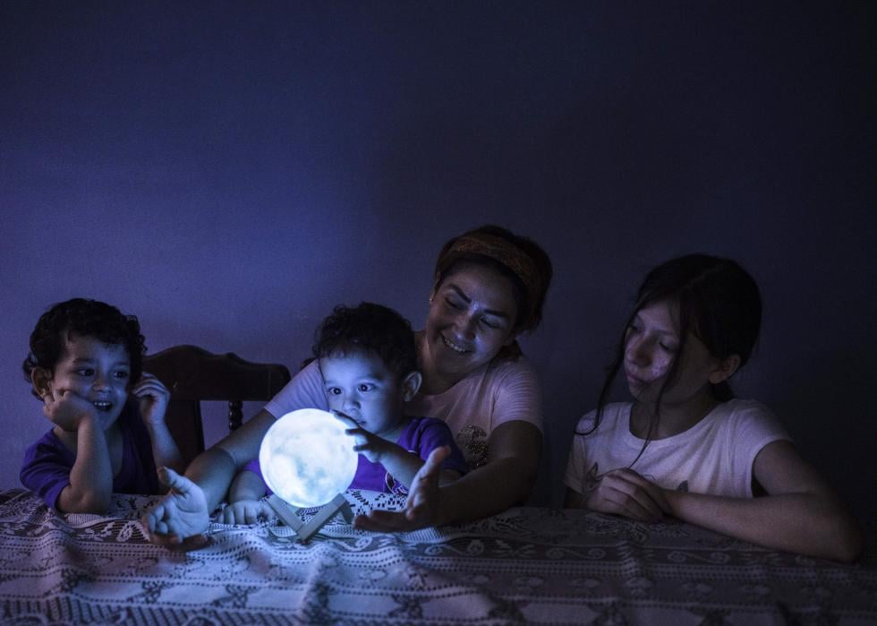 Madre y tres hijos en la cama jugando con orbe brillante