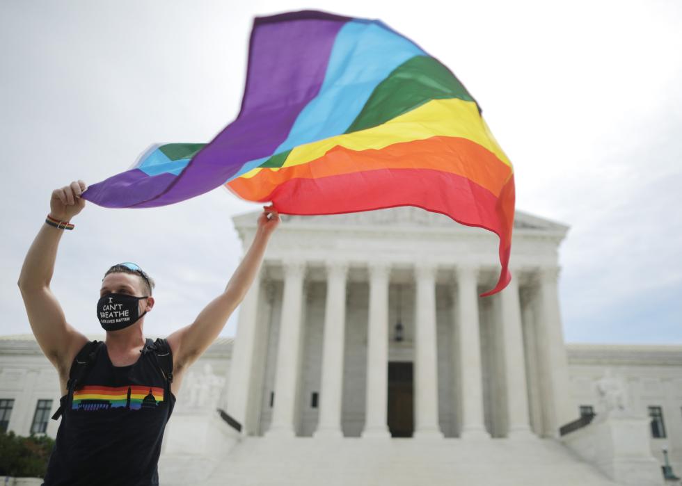 Joseph Fons holds a Pride Flag in front of the Supreme Court building