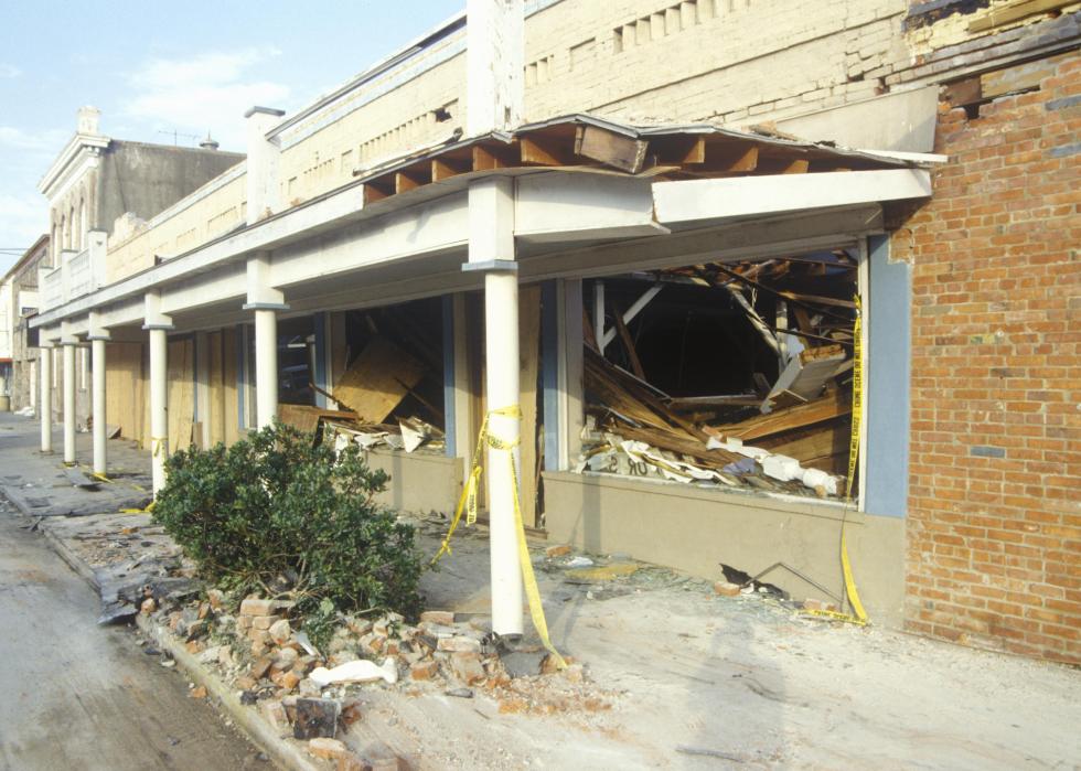 Yellow caution tape hangs from columns outside destroyed storefronts.